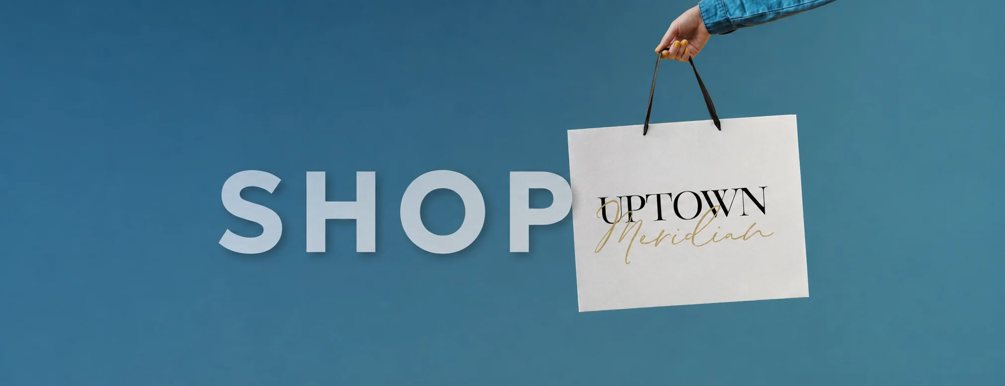Shop Uptown Meridian: a hand holding an Uptown Meridian shopping bag